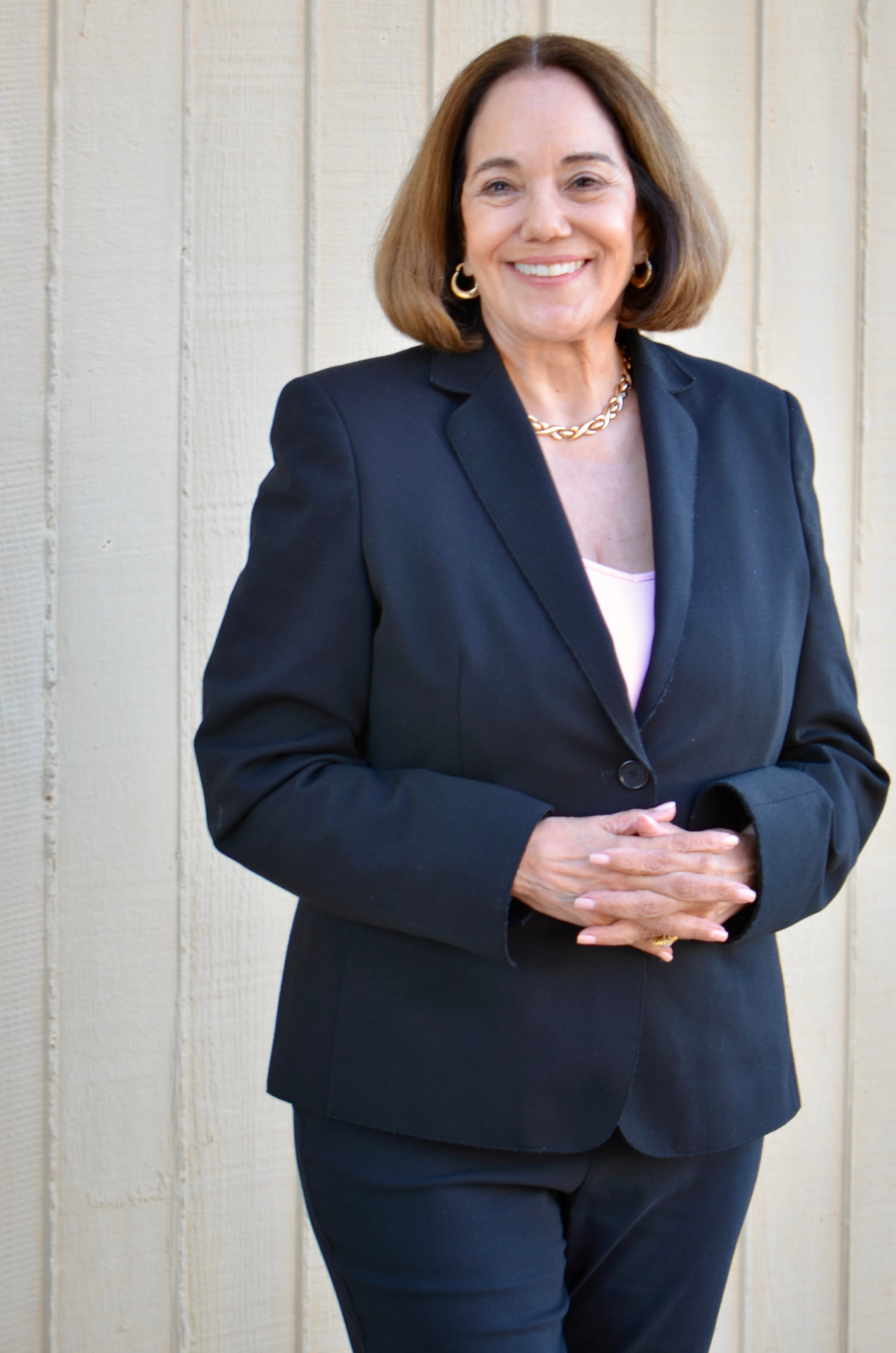 Maria Bondonno in a navy suit standing against a light wall